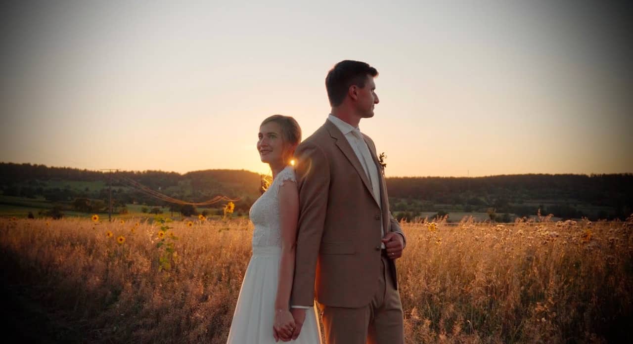 Daniel und Christina stehen im Abendlicht in einem Feld mit Sonnenblumen.